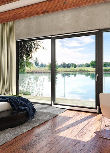 Baie vitrée coulissante aluminium ouvrant sur une terrasse au bord de l'eau